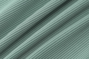 Macro shot of sage green ribbed knit fabric texture showing elasticity and soft drape