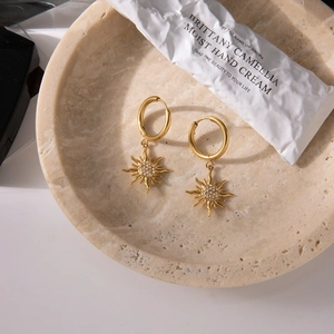 Elegant gold sun flower earrings with rhinestones on a minimalist marble tray