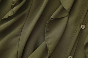 Detailopname van donkergroene blouse met gelaagde ruches en bijpassende knopen