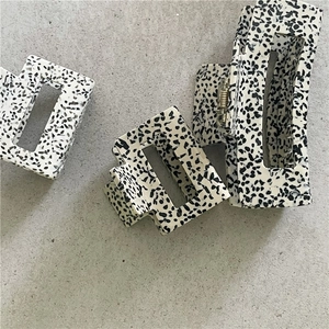 Detailed view of spotted acetate hair claws with gold-tone springs on a grey surface