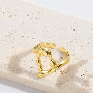 Detail of a vintage knot-shaped gold open ring on a minimalist beige stone base