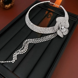 Close-up of a silver rhinestone floral choker with cascading tassel chains on black velvet