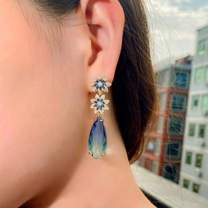 Close-up of elegant gradient blue sapphire teardrop earrings worn on a model