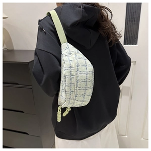 Detail of light green textured crossbody bag with zip closure on model back view