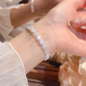 Detailed view of silver daisy flower link bracelet worn on wrist with elegant lighting