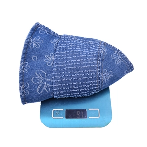 Denim bucket hat with white flower print and fringe detail on electronic scale weighing 91g