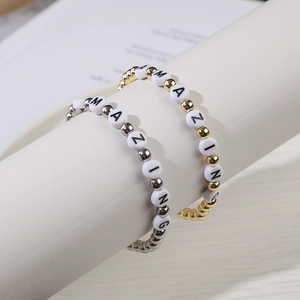 Detail of silver and gold beaded bracelets featuring white AMAZING letter beads