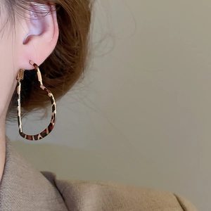 On-ear shot showing large heart-shaped leopard print earrings with gold metal base