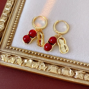 Detail of gold peanut earrings featuring red glass beads on vintage velvet display