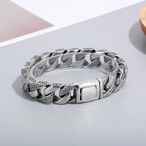 Macro detail of vintage silver Cuban chain bracelet with engraved Greek key patterns
