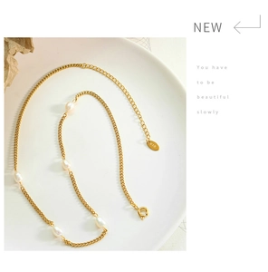 Macro shot of 18K gold chain with freshwater pearls and K18 hallmark tag in a tray