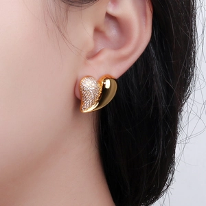 Elegant heart-shaped gold studs with sparkling cubic zirconia on model's ear