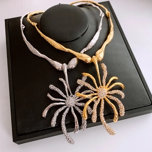 Gros plan de colliers fleurs en strass or et argent sur des supports noirs