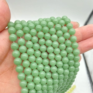 Macro shot of green luminous round beads for DIY jewelry held in hand for size comparison