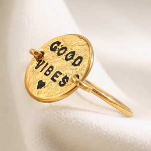 Macro shot of gold-plated stainless steel ring with GOOD VIBES lettered round charm