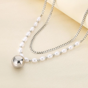 Detail of double-layer necklace featuring white pearls and a polished silver ball pendant