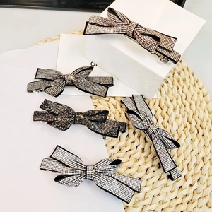 Detailed view of handmade bow hair clips featuring sparkling rhinestones on black fabric