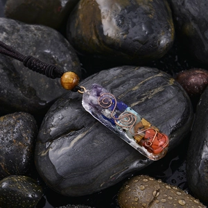 Macro shot of 7 chakra resin pendant with crystal chips and copper spiral on wet stones