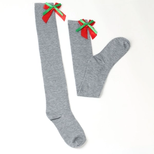 Detail of grey over-knee socks with festive red and green ribbon bow decoration
