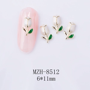 Macro shot of 6x11mm white tulip nail art charms with gold trim on a pink manicure display
