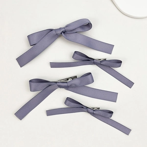 Close-up of four lavender satin bow hair clips showing silky texture and metal duckbill clips