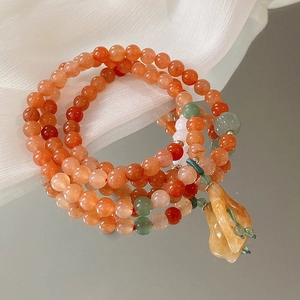 Makro-Detail von rotem Achat-Armband mit grünen Jadeperlen und gelbem Steinanhänger
