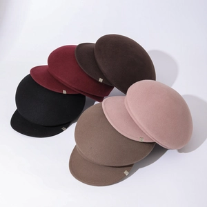 Multiple colors of wool felt newsboy caps showing side metal buckle detail and fabric texture
