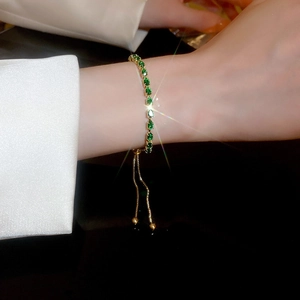 Close-up of adjustable gold bracelet featuring sparkling green teardrop emerald zircons