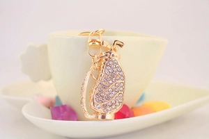 Detail of a golden golf bag keychain with sparkling rhinestones on a heart dish