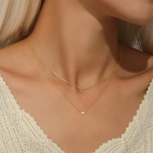 Close-up of layered gold silver necklace with zircon heart and star pendants on a model