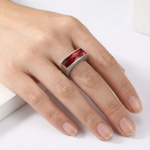 Detailed macro view showing the red rectangular gemstone and brushed gold steel ring texture