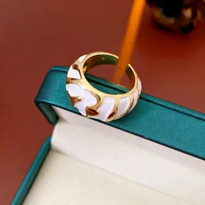 Vintage gold wave ring with white enamel detail on a premium green jewelry box