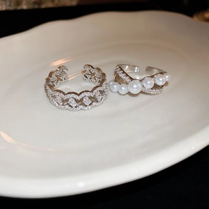 Detailed view of pearl and zircon rings on a white tray against a black background