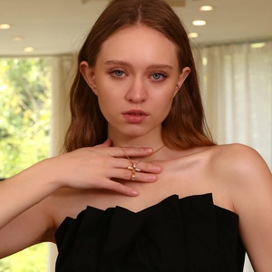 Detail of 18K gold plated cross necklace with multi-colored crystals on a female model