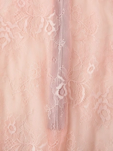 Close-up of pink floral lace fabric showing fine embroidery and delicate mesh texture
