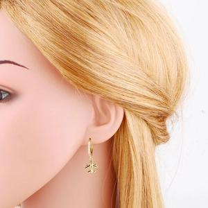 Close-up of golden starburst airplane earrings with inlaid sparkling zircon stones