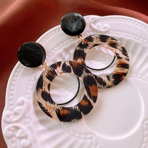 Detail of leopard print hoop earrings with black studs on a vintage ceramic plate