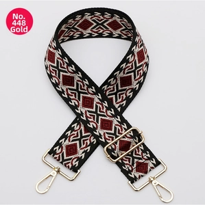 Close-up of adjustable wide geometric patterned strap with gold metal swiveling hooks