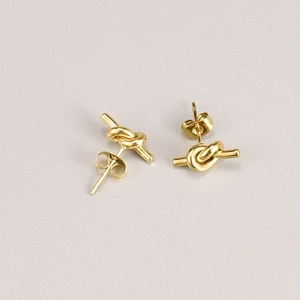 Minimalist knot design 18K gold plated titanium steel stud earrings on a grey background