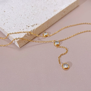 Close-up of gold stainless steel layered necklace with three round-cut cubic zirconia charms