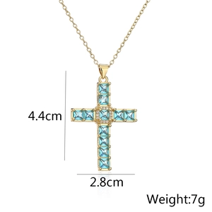 Macro shot of gold-plated cross pendant with blue crystals and size specs 4.4x2.8cm