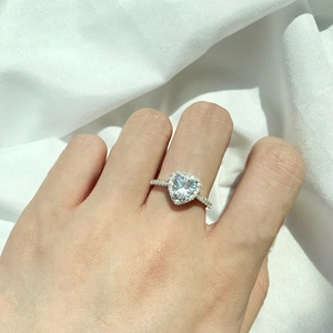 Close-up of heart-shaped halo diamond ring in sterling silver worn on a finger
