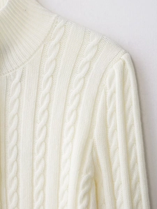 Detailed close-up of cream white cable knit sweater featuring classic texture and soft fabric