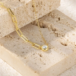Detail of S925 silver gold-tone necklace with mixed chain links and round zircon pendant