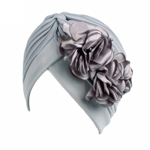 Detail of silver gray elastic turban hat featuring a large 3D floral decoration