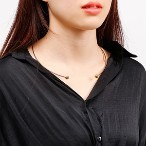 Close-up of a minimalist gold C-shaped titanium steel collar necklace with spherical ends