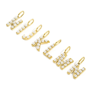 Macro detail of golden letter charms H to N with white pearls for DIY jewelry making