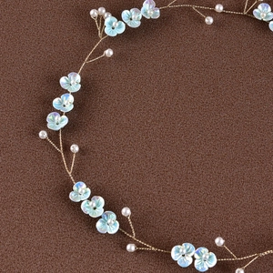 Close-up of bridal headpiece with blue resin flowers, pearls, and flexible gold wires