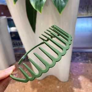 Detail of dark green matte headband with wide wavy teeth for secure hair styling