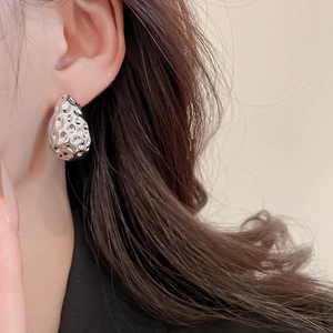 Close-up of silver-toned twisted drop earrings with hammered texture on a model